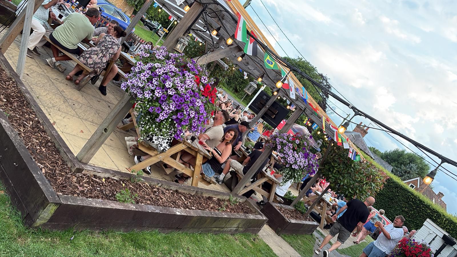 Flower beds and planters in bloom in the pub garden, with seating beyond