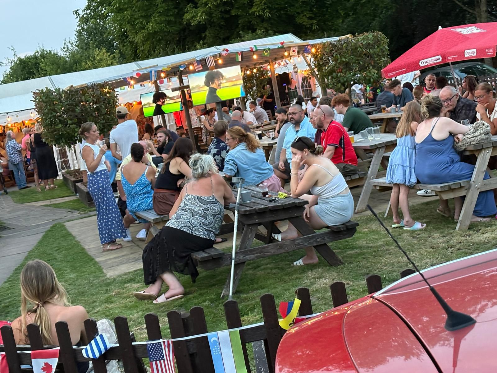 Groups of people sitting and standing around tables in the pub garden